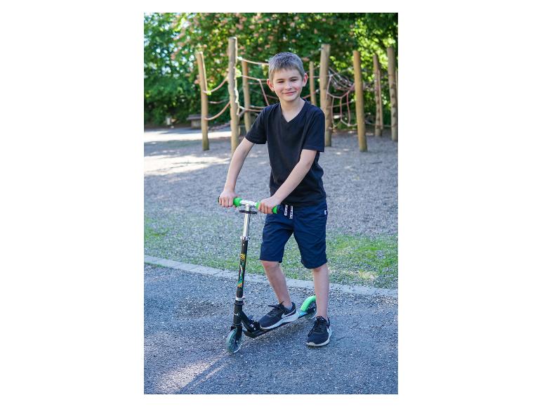Lächelnder Junge mit Roller auf einem Spielplatz