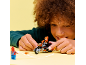 Kind spielt mit Spielfiguren und einem Motorrad auf gelbem Hintergrund.