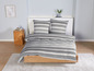 Ein Bett mit gestreiftem Bettwäsche in Grau und Weiß.