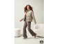Frau in beiger Steppjacke, brauner Hose und Sneakern.
