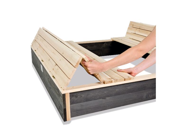 Holzsandkasten mit klappbaren Bänken, eine Person stellt eine Bank ein.