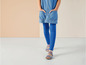 Ein Mädchen trägt blaue Leggings und ein Jeanskleid mit blauen Sandalen.