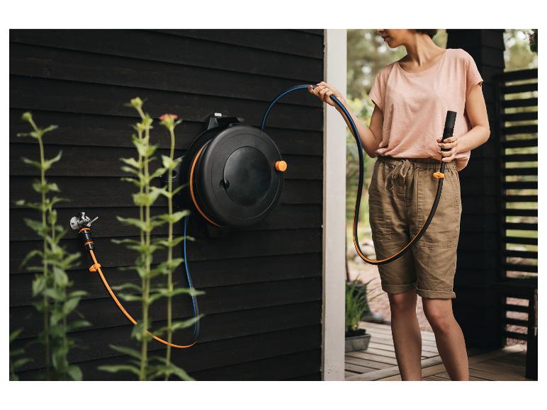 Frau benutzt eine wandmontierte automatische Gartenschlauchbox.