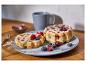 Waffeln mit Beeren und Puderzucker auf einem Teller, mit einer Kaffeetasse im Hintergrund.