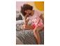 Eine Frau im Bett trägt einen rosa Damen-Pyjama mit Minnie-Maus-Motiv.