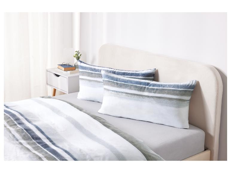 Ein Bett mit gestreiftem Bettbezug und Kissenbezügen.