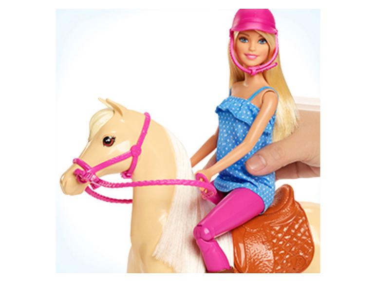 Barbie-Puppe reitet auf einem Spielzeugpferd, gehalten von einer menschlichen Hand.