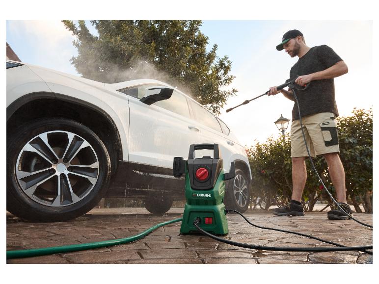 Ein Mann wäscht sein weißes Auto mit einem Parkside Hochdruckreiniger.