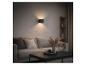 Schwarze Wandleuchte beleuchtet ein Wohnzimmer mit Sofa und Couchtisch.