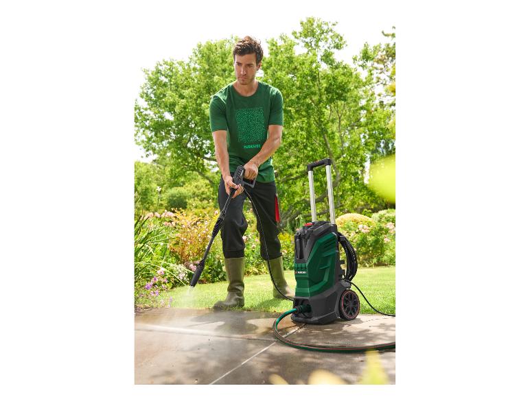 Mann reinigt eine Terrasse mit einem Hochdruckreiniger im Garten.