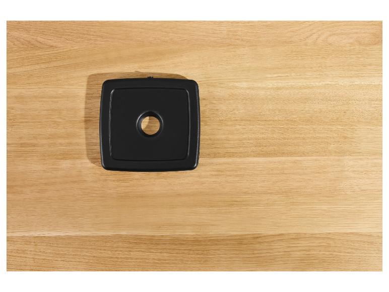 Schwarze quadratische Unterlage auf einer Holzplatte.