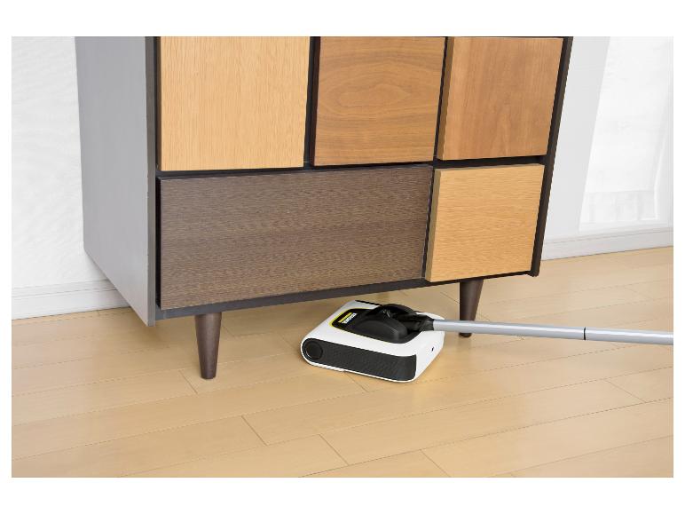 Elektrischer Besen reinigt unter einem Holzschrank mit mehrfarbigen Türen.