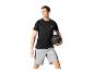 Mann in schwarzem Sport-T-Shirt und grauen Shorts hält einen schwarzen Trainingsball.