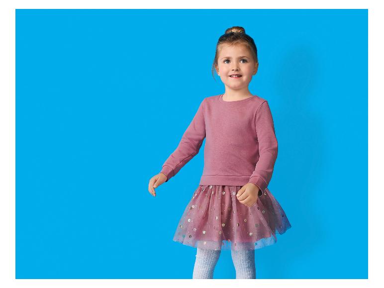 Mädchen in rosa Sweatshirt und Tüllrock mit Pailletten.