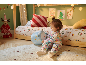 Ein Kleinkind spielt mit einem Plüschtier im weihnachtlich dekorierten Kinderzimmer.