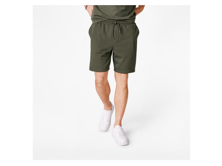 Mann in weißen Sneakern und olivgrünen Shorts.