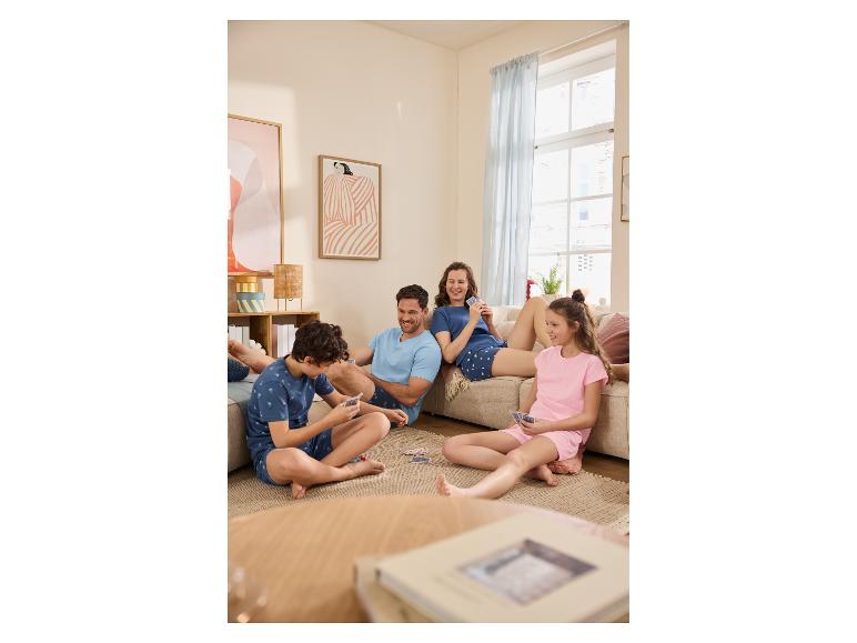 Familie im Pyjama spielt Karten im Wohnzimmer.