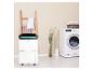 Weißer Luftentfeuchter neben einer Waschmaschine in einem modernen Waschraum.