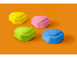 Vier farbenfrohe, samtige sechseckige Kuchen auf orangefarbenem Hintergrund.