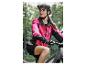 Frau in pinker Radjacke und schwarzem Helm auf einem Mountainbike.