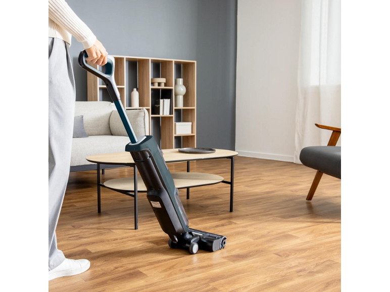 Person reinigt Holzboden mit Nass-Trocken-Staubsauger in einem modernen Wohnzimmer.
