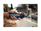 Ein blauer Philips Rasierer wird unter dem Wasserhahn gereinigt.