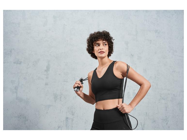 Frau in Sport-Top und Leggings hält ein Springseil.