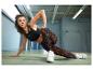 Frau in schwarzem Sport-BH und bedruckten Leggings, beim Sport.
