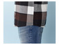 Ein Teil eines karierten Hemdes in Schwarz, Weiß und Braun sowie blaue Jeans.