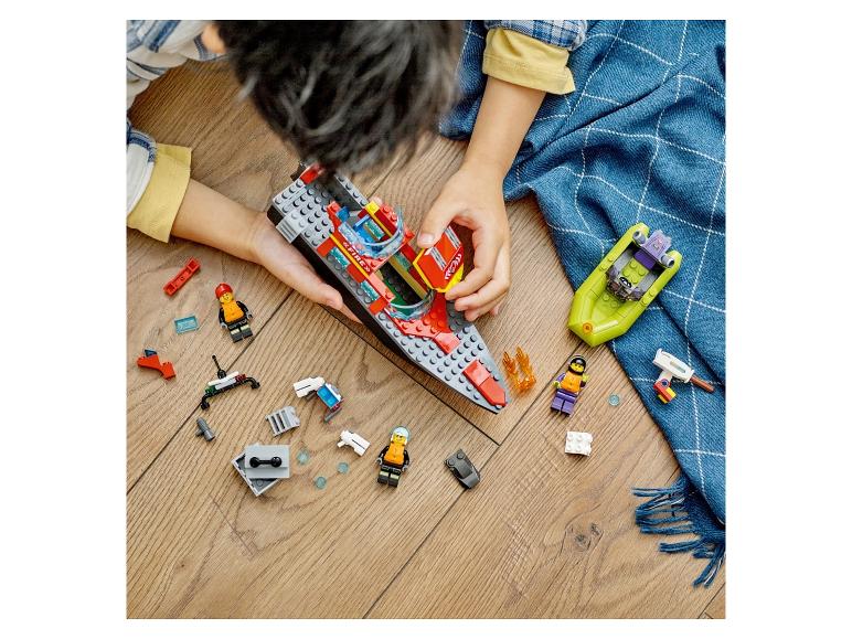 Kind spielt mit Spielzeugbooten und Figuren auf Holzboden.