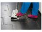Eine Person in blauen Hosen und rosa Sandalen benutzt einen Bodenreiniger auf dunklen Fliesen.