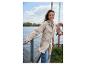 Frau in beiger Regenjacke und Jeans, lächelnd am See.