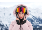 Frau in rosa Skijacke mit Kapuze und Skibrille in den Bergen