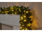 Weihnachtsgirlande mit warmweißen LED-Lichtern auf einem weißen Kaminsims.