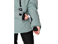 Person in mintgrüner Jacke mit schwarzem Reißverschluss und weißem Zettel in der Ärmeltasche.