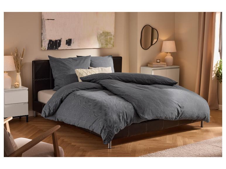 Modernes Schlafzimmer mit Polsterbett, grauer Bettwäsche mit geometrischem Muster und weißen Nachttischen.