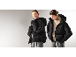 Frau in schwarzer Daunenjacke, Pullover und grauer Hose.