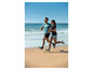 Zwei Personen laufen in Sportkleidung am Strand.