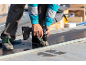 Ein Handwerker montiert Metalldachplatten mit einem Akku-Bohrschrauber.
