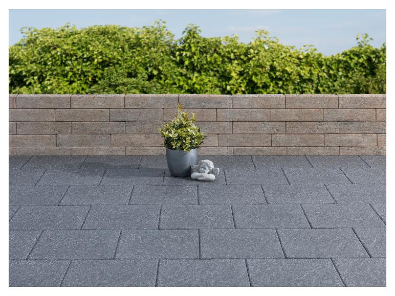 Graue gepflasterte Terrasse mit Ziegelmauer, Topfpflanze und Engelsfigur.