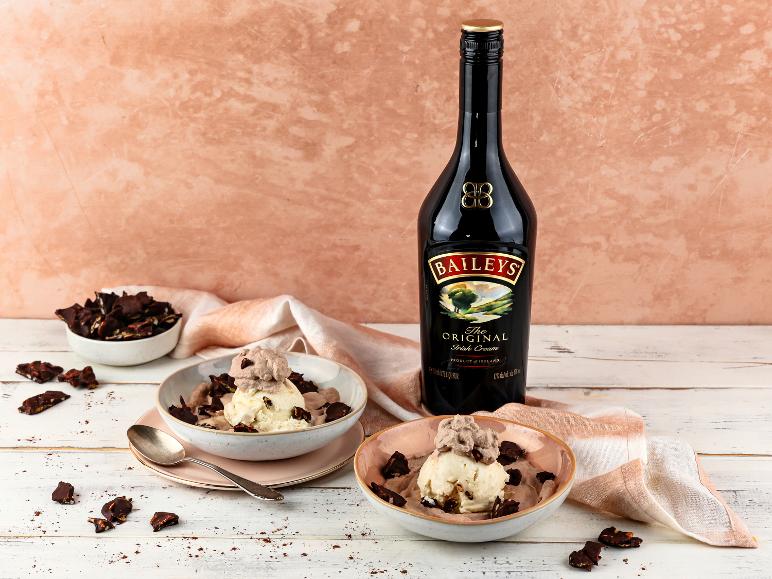 Flasche irischer Sahnelikör mit zwei Schalen Eis und Schokoladenrinde.