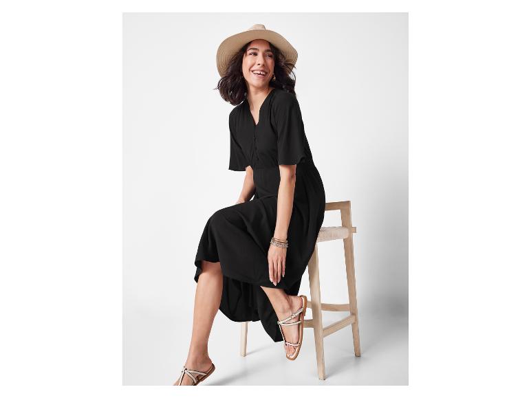 Frau in schwarzem Midikleid und Strohhut.