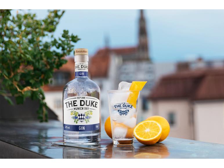The Duke Munich Dry Gin Flasche und Glas mit Eis und Orangenschale, mit Orangen daneben.