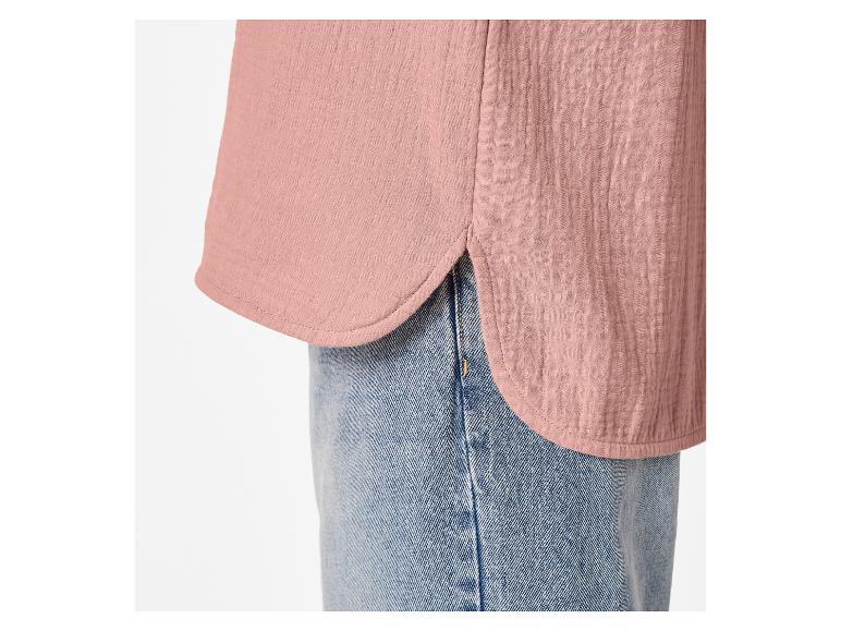 Detail eines rosa Musselinhemdes mit abgerundetem Saum und blauen Jeans.