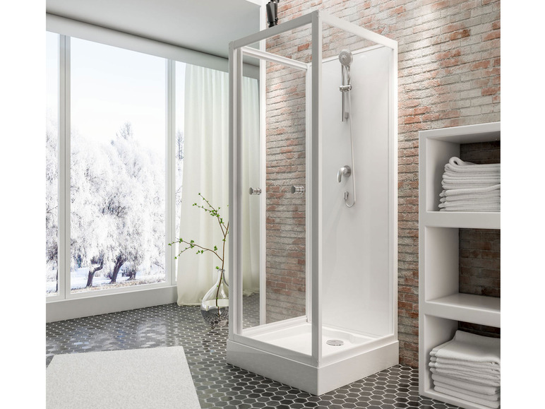 Eine weiße Duschkabine mit Glastür, vor einer Backsteinwand.