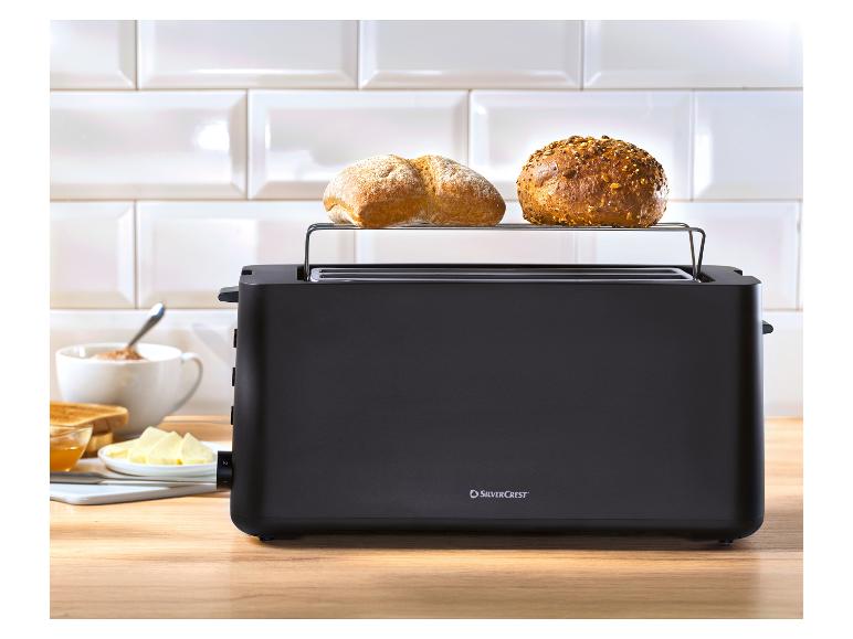 Schwarzer SilverCrest Toaster mit Brötchen auf dem Rost und Frühstück auf Holztisch.