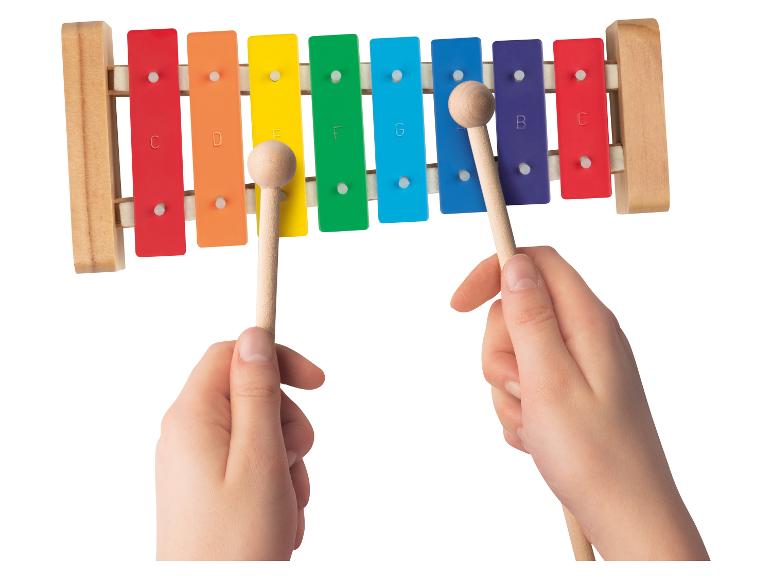 Ein Kind spielt ein buntes Xylophon mit zwei Holzschlägeln.