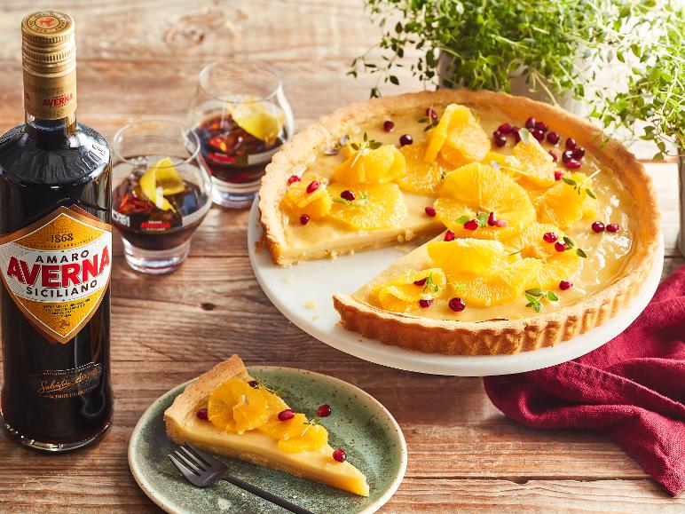 Flasche dunkler Likör, Orangen-Granatapfel-Tarte und zwei Gläser Getränk auf einem Holztisch.