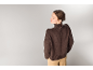 Eine Frau in einem braunen Rollkragenpullover und einer beigen Hose von hinten gesehen