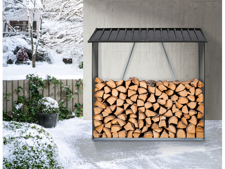 Gestapeltes Brennholz in einem schwarzen Holzregal, mit einer verschneiten Winterlandschaft im Hintergrund.